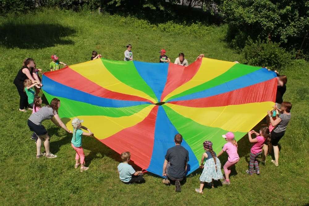 Kinder spielen mit großem bunten Schwungtuch